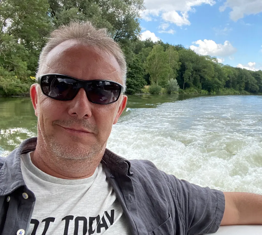 Daniel Hügli mit Sonnenbrille im Freien, im Hintergrund ein Fluss
